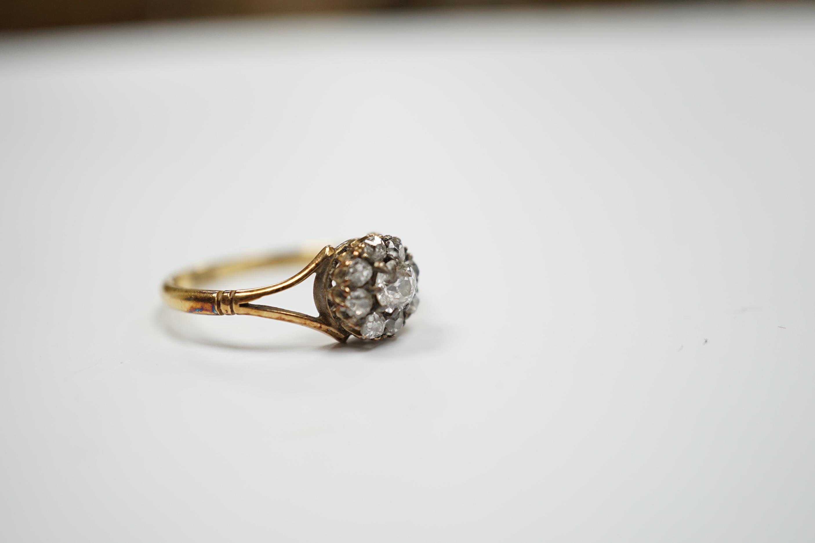 An early 20th century 18ct and old round cut diamond set circular cluster ring, size Q, gross weight 2.7 grams.